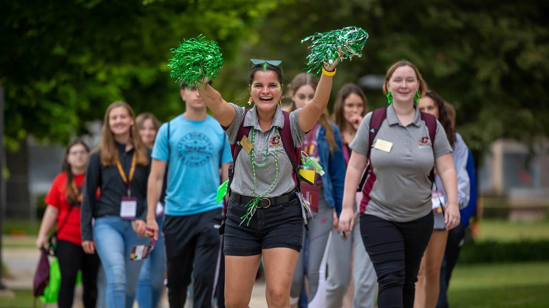 A group of students walking with pom poms during a tour around Central Michigan Universities campus.