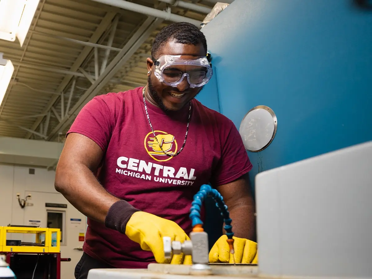 A student in a Central Michigan University shirt works with power tools.