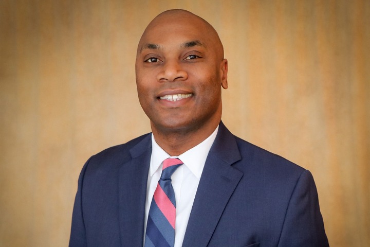 A man in a suit and tie smiling in a headshot photo.