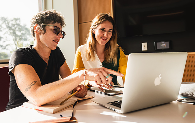 A faculty member aiding in guiding a student with work on a computer