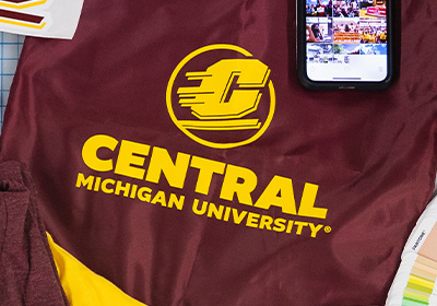 Central Michigan University Action C combination mark in one-color gold, placed on a maroon vinyl bag.