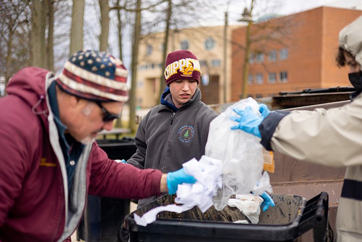 CMU student Eric Urbaniak helps to sort garbage and recyclables in front of the University Center on Thursday, April 7.