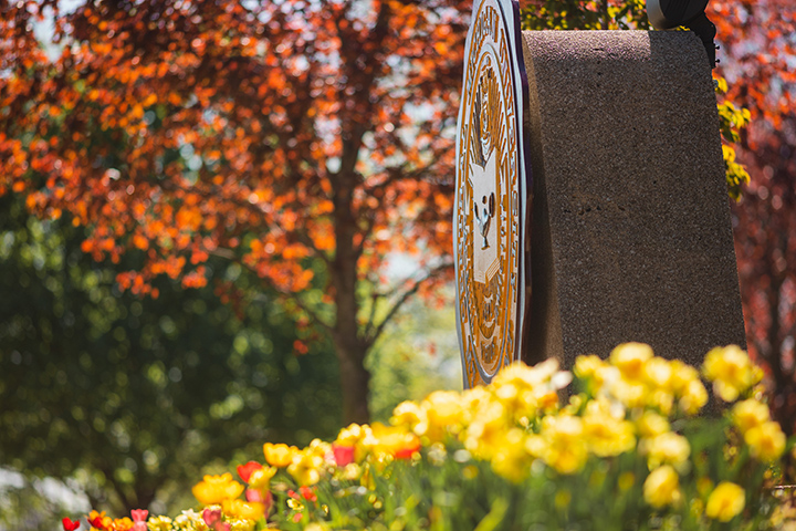 The CMU seal blends in with the colors of the surrounding flowers and trees.