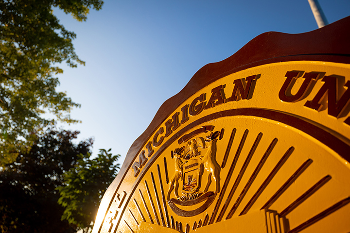 The morning sun shines through over the CMU seal, located in front of Warriner Hall.