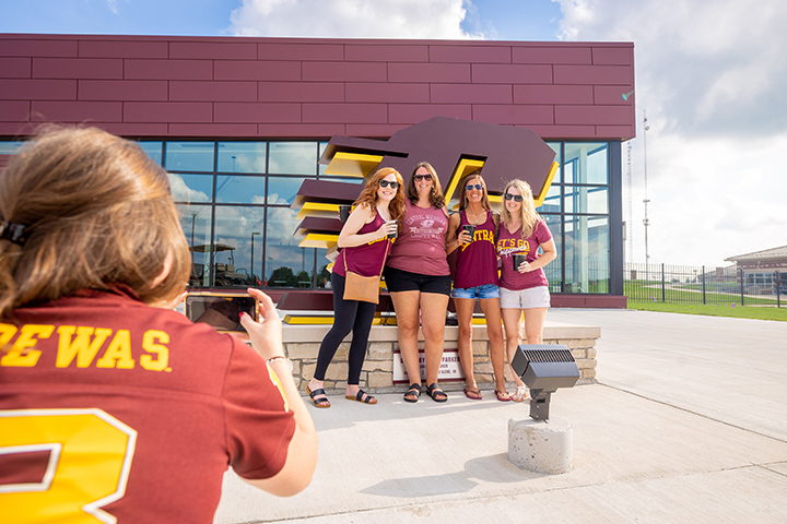 A group of CMU Alumni pose for a photo in front of the CMU Chippewa Champions Center during the 2022 Alumni Reunion Weekend.