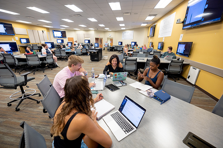 A wide shot of a classroom where students go over the syllabus during the first day of classes.