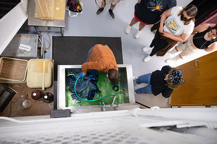 A top-down view of a faculty member working on a photo lab surrounded by students.