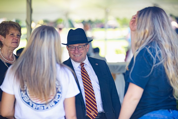 President Bob Davies greets two CMU students.