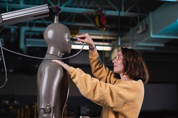 A student plugs an electrical cable into a mannequin.