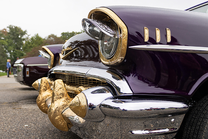The front bumper and lights of a maroon, gold and silver classic car.