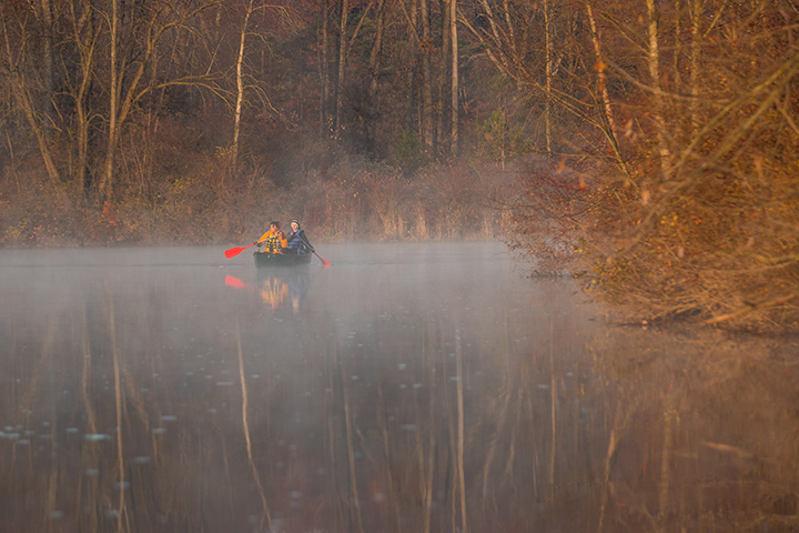 Two students paddle down the Chippewa River on a foggy morning.
