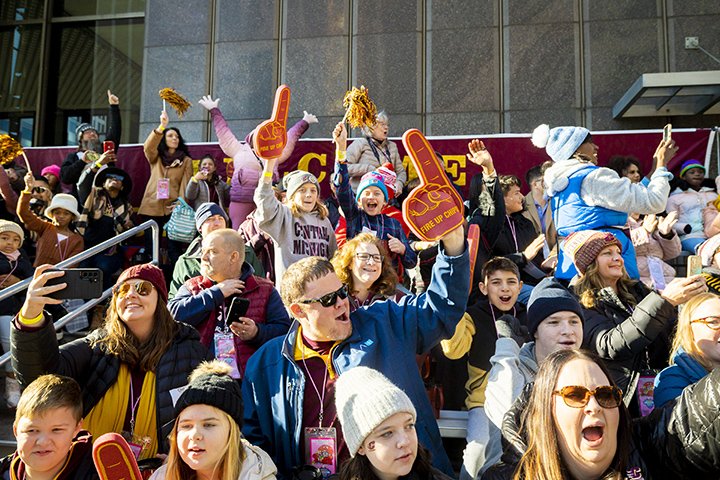 A large group of people wearing CMU clothing, cheer from the grandstands at America’s Thanksgiving Day Parade.