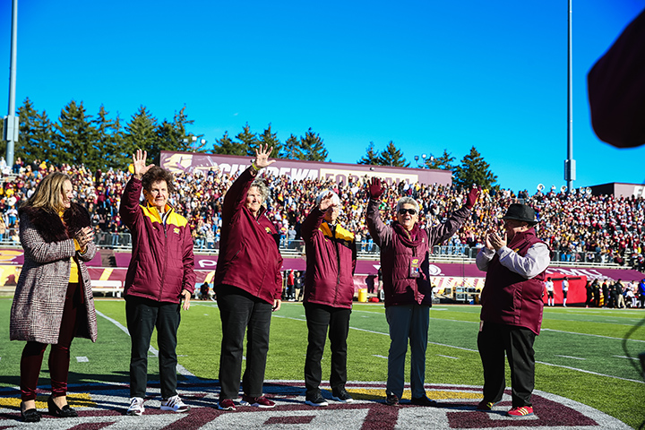 CMU's Homecoming Grand Marshals wave to the crowd while standing on the field inside Kelly/Shorts Stadium.
