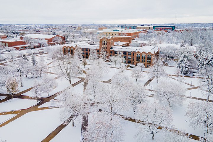 An aerial view of Warriner Hall as snow covers trees and the CMU campus.