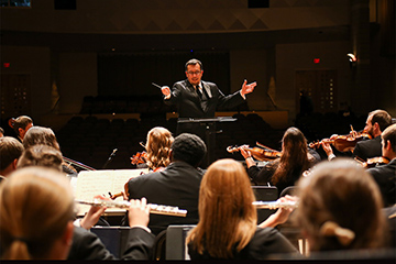 José-Luis Maúrtua conducts an orchestra.