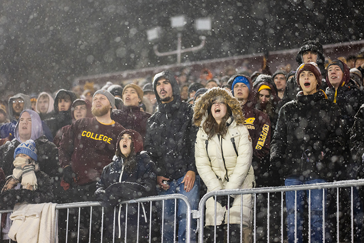 CMU students cheer from the stands on a snowy night at Kelly/Shorts Stadium.