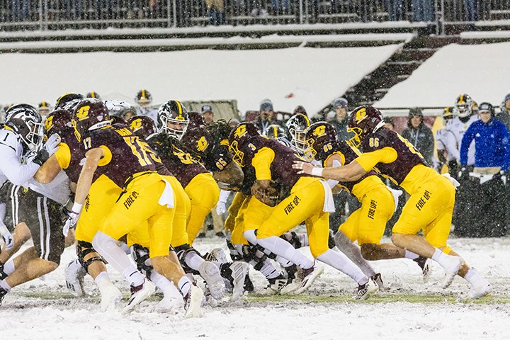 The CMU offense does a running play against Western Michigan University in the snow.