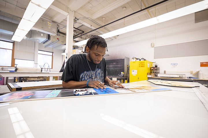 Student De'Sna Pruiett sits at a table working on his studio art project.