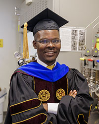 Nicholas Banahene poses in his cap and gown before graduating with his doctorate degree.
