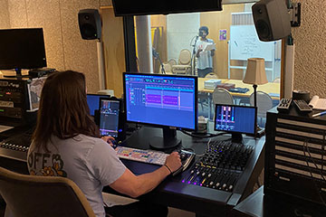 A Central Michigan University student in Moore Hall records a student actor performing a radio drama.