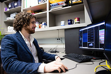 Emmanuel Crespo sits at a computer, performing an experiment.