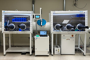 A hooded and vented laboratory cabinet with gloves used for battery research.