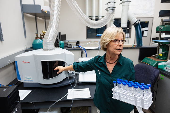 Monaliza Sirbescu points to test equipment used to analyze rock samples.