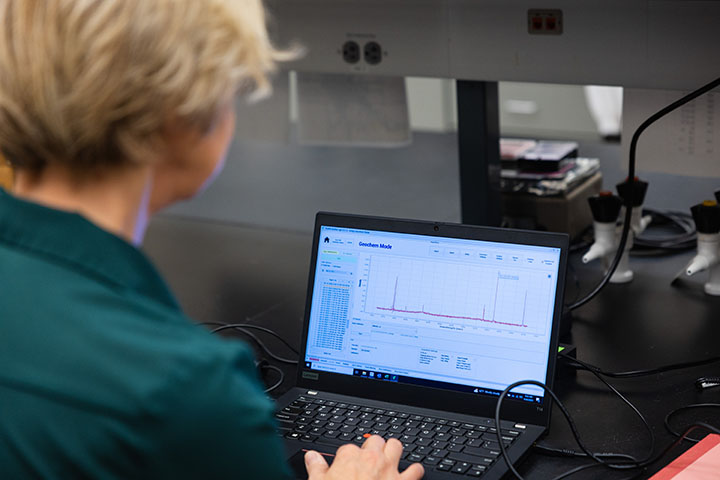 Monaliza Sirbescu analyzes rock sample data with a laptop computer.