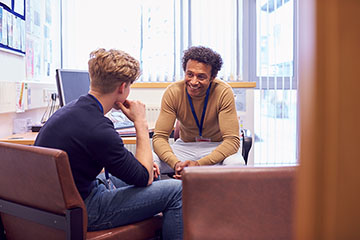 A college student talks to a counselor in an office.