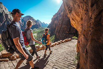 Three people hike down a brick path in Utah's Zion National Park.