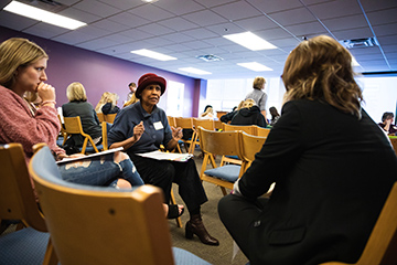 A group of people sit in chairs at the Diversity Symposium.