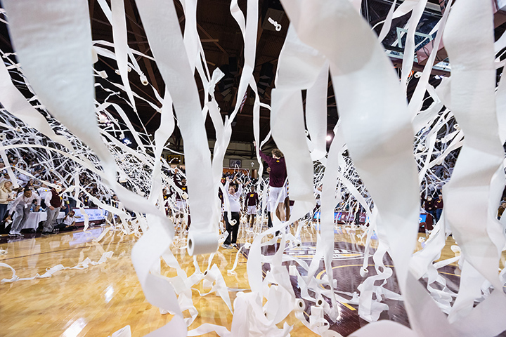 Hundreds of toilet paper rolls fall from the sky and onto the court inside McGuirk Arena.