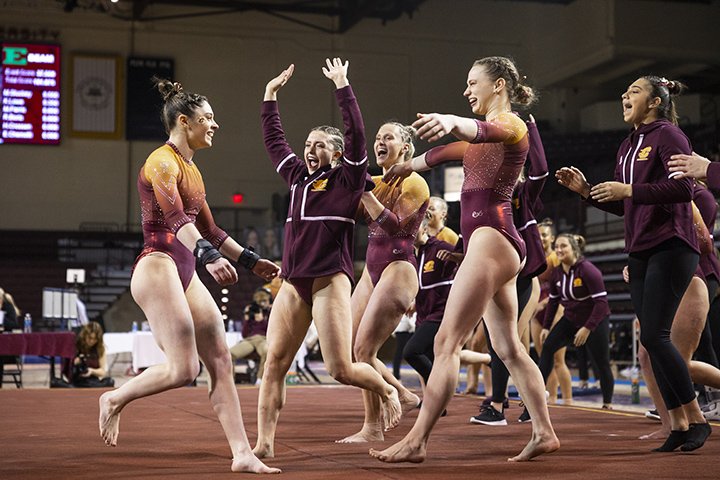 Members of the CMU women's gymnastics team celebrate after defeating Eastern Michigan.