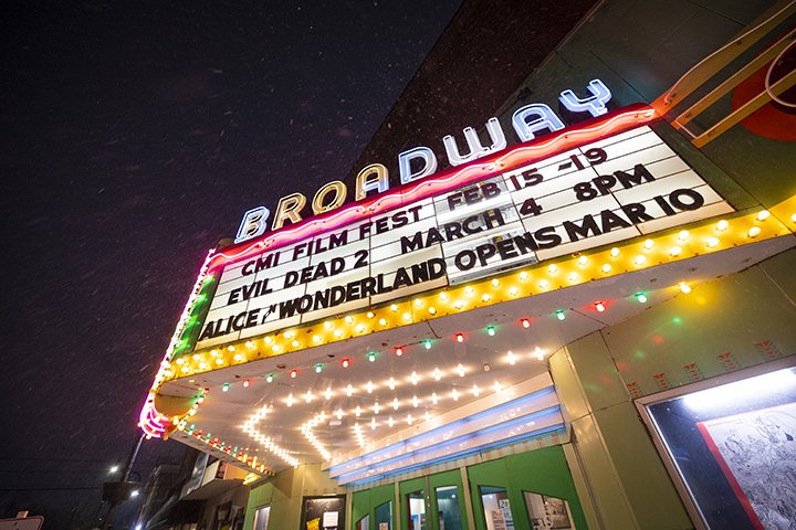 A movie theater marquee is lit up at night with the words 