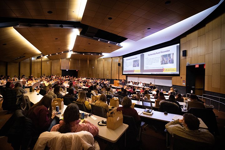 Hundreds of teacher candidates sit in a large auditorium.