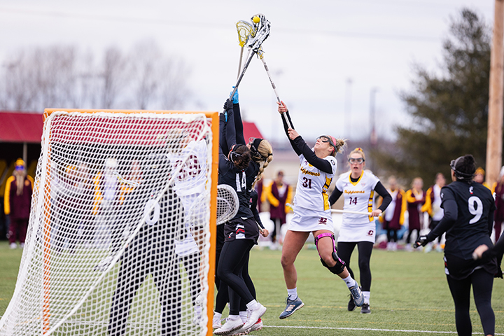 Women's lacrosse players go after a ball in the air.