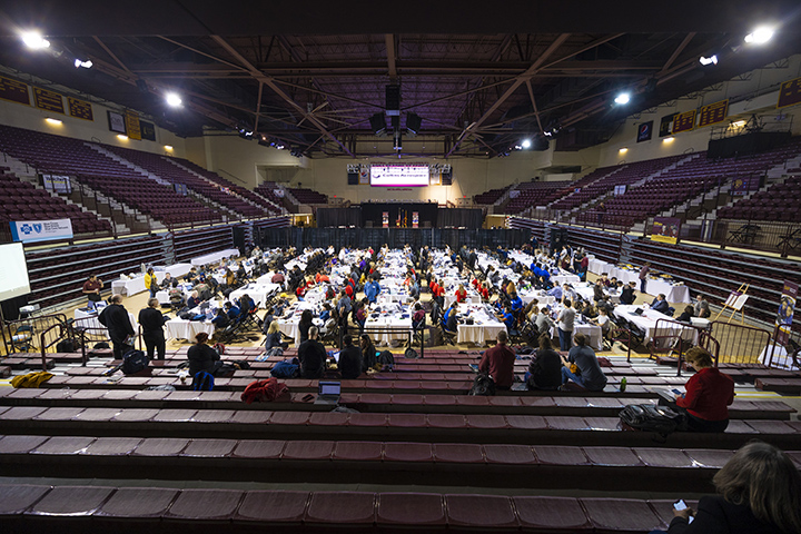 A wide angle view of a basketball arena where hundreds of people work at tables in a business competition.