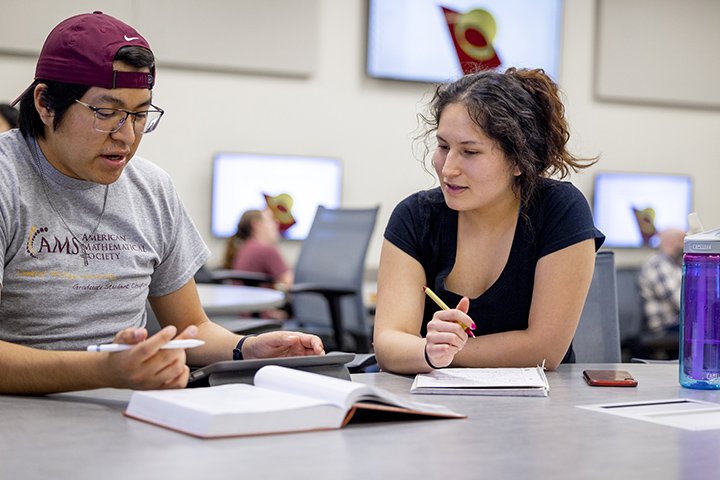 Two mathematics students sit at a table studying together.