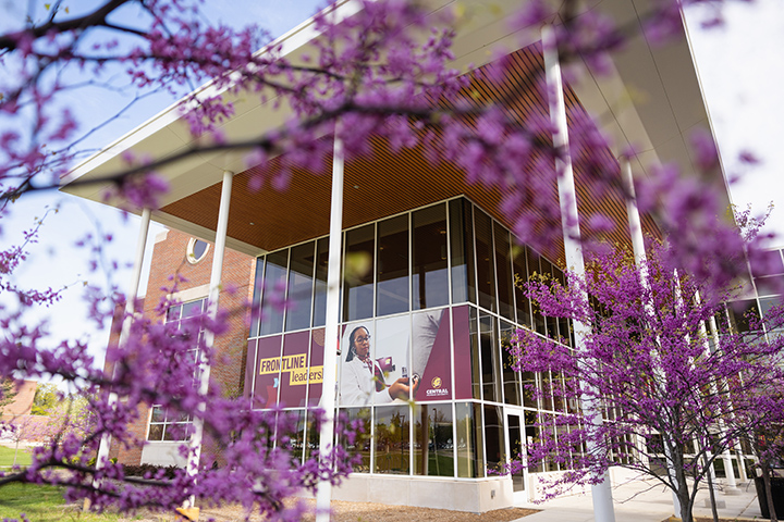 Trees with purple flowers are in bloom outside the Health Professions Building.