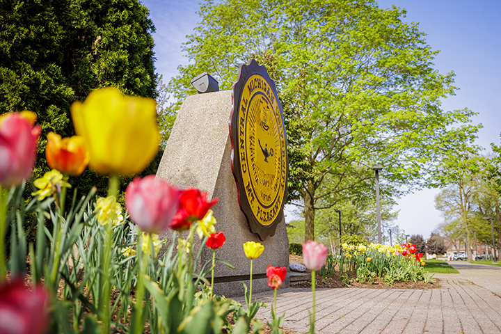 Colorful flowers in bloom next to the CMU seal.