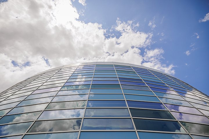 Looking up towards the sky, the clouds reflect on the windows of the Charles V. Park Library.