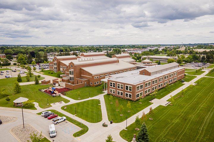 An aerial view over the College of Medicine and Health Professions Building with overcast skies overhead and freshly cut green lawns surrounding the buildings.