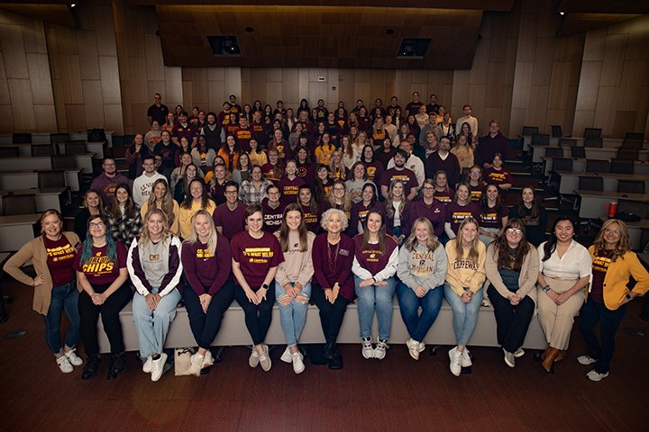 Inside an auditorium, teacher candidates and faculty members pose for a group photo.