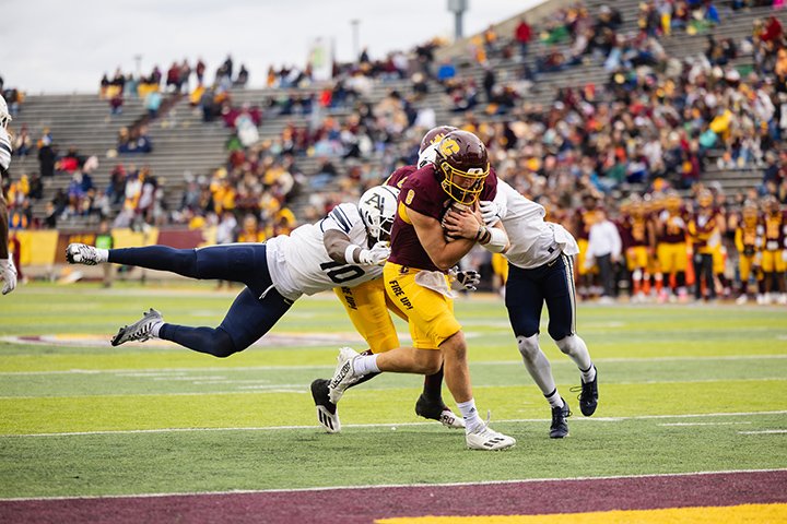 A CMU football player gets tackled by two Akron players as he tries to cross the goal line.