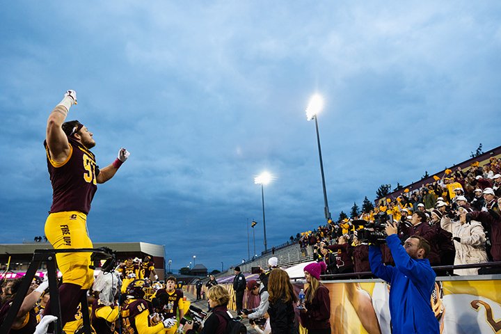 A CMU football player conducts the marching band from the sideline.