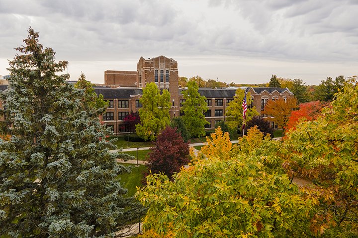 Fall colors in Warriner Mall as trees of green, orange, red and yellow surround Warriner Hall with an overcast sky overhead.