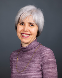 A woman in a purple shirt smiles at the camera.