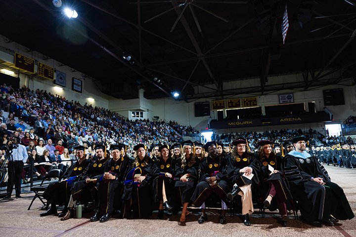 A wide-angle view of the College of Medicine's graduating class as they sit in chairs on the floor of McGuirk Arena.