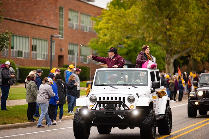 President and Mrs. Davies throw candy from a white Jeep during the Homecoming parade.
