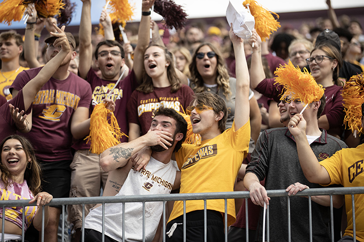 A group of CMU students watching the CMU-New Hampshire football cheers from the stands.